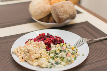 Two different salad vinaigrette and Olivier on a white plate.