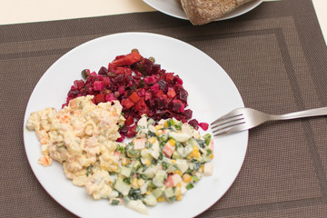 Two different salad vinaigrette and Olivier on a white plate.