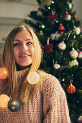 Portrait of beautiful woman enjoying near Christmas tree.