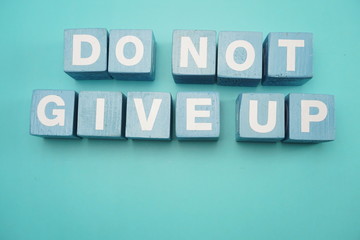 Do Not Give Up word made from wooden cubes with letters alphabet on blue background