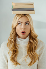 close up of adult woman with funny face expression and books on head