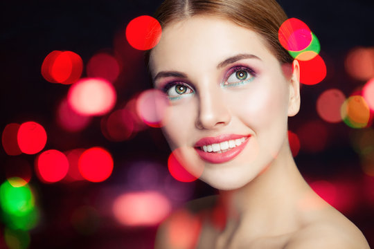 Young fashion woman with makeup smiling on colorful glitter background