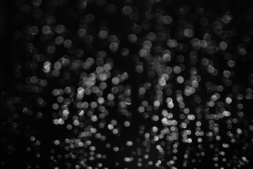 bokeh of lights made by raindrops on a windows illuminated by a torch, abstract background or texture shot