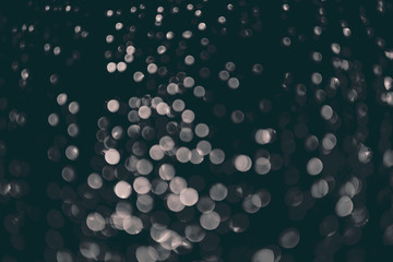 bokeh of lights made by raindrops on a windows illuminated by a torch, abstract background or texture shot