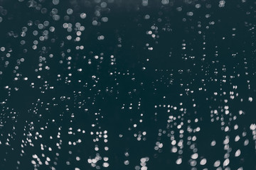 bokeh of lights made by raindrops on a windows illuminated by a torch, abstract background or texture shot