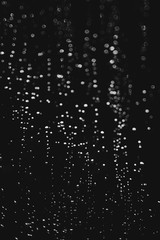 bokeh of lights made by raindrops on a windows illuminated by a torch, abstract background or texture shot