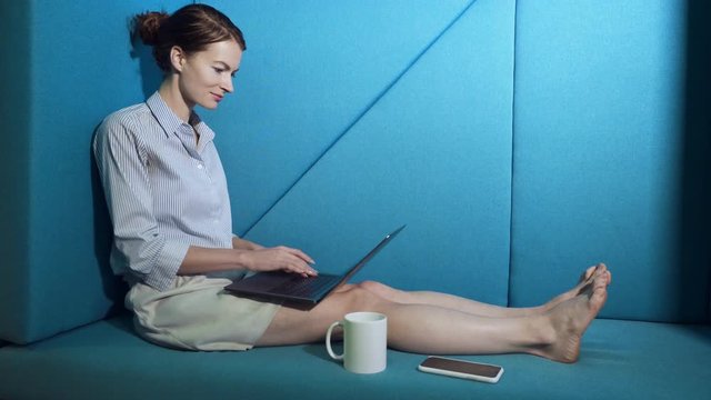 Business woman sitting on the couch and working on the laptop computer.