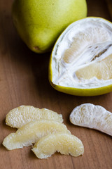 Big pomelo fruit, a big citrus fruit that has to be peeled.  Shot on wooden table surface. Selective focus.