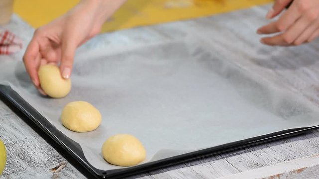 Yeast buns before baking, lie on baking sheet with baking paper. Cooking process.