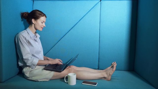 Business woman sitting on the couch and working on the laptop computer.