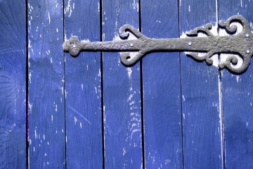 Detail of blue wooden gate with rusty iron hinge