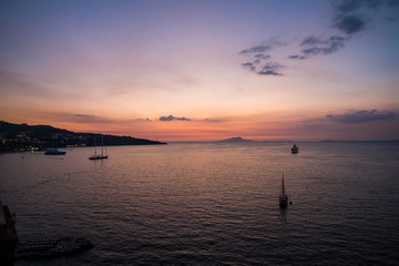 Travel and enjoy life concept with many boats in the middle of the sea with islands in background. Wanderlust with pink sunset sky coloured and people traveling away for the next adventure destination