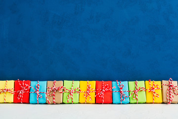 Christmas gifts in colorful paper in one line with blue background