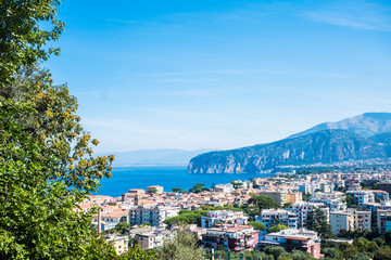 Fototapeta na wymiar Above view of Sorrento Naples Campania Italy holiday beautiful city place. Mediterranean scenic place with blue sea and high cliffs mountains. Naples and Vesuvio in background