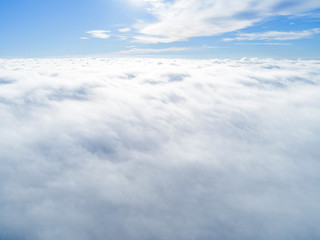 Aerial view White clouds in blue sky. Top view. View from drone. Aerial bird's eye view. Aerial top view cloudscape. Texture of clouds. View from above. Sunrise over clouds
