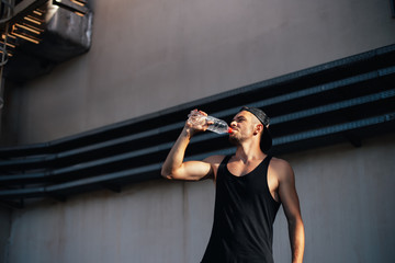 Young sporty man drinking water from bottle