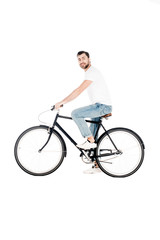 Handsome smiling young adult riding bicycle while looking at camera isolated on white