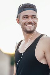 Smiling man in headphones listening to music outdoors