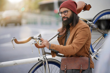 Hipster guy in town carrying fixie bicycle