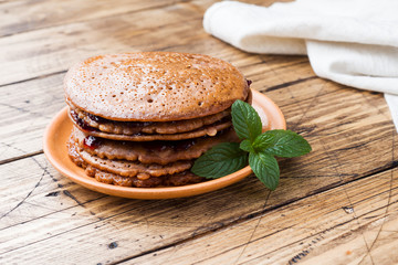 Fototapeta na wymiar Chocolate pancakes with berry jam and mint for Breakfast on wooden background