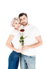 Beautiful couple with flower hugging while looking at camera isolated on white