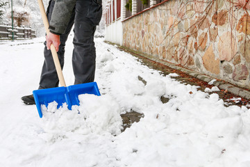 Man removing snow from the sidewalk after snowstorm.