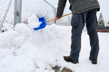 Man removing snow from the sidewalk after snowstorm.