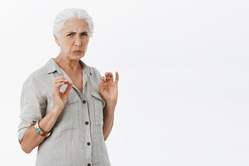 Woman think it disgusting. Portrait of displeased senior woman with white hair frowning and grimacing seeing creepy dissatisfying thing expressing aversion and dislike posing over gray background