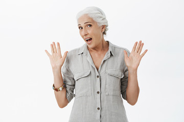 Old woman feleing tired not wanting participate in event. Portrait of uninterested and uninvolved cute granny with white hair raising palms in surrender turning away rejecting to be part of action