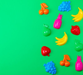 multicolored plastic toys fruits on a green background