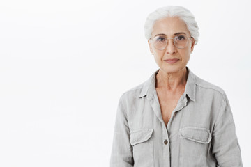 Studio shot of wise and intelligent skillful senior female doctotr in glasses with gray hair...