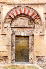 Fototapeta na wymiar Golden door in the Mosque Cathedral in Cordoba, Spain. Exterior wall - famous landmark in Andalusia