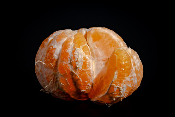 Half peeled mandarin on a black background close-up