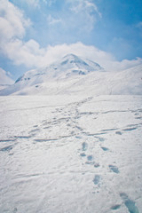 Fototapeta na wymiar foot step on snow hill with blue sky