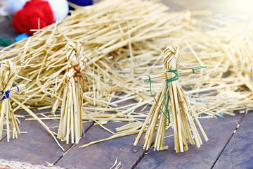 Closeup of a straw doll on a wooden table.