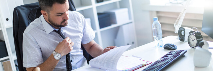 A man is sitting in the office and scrolls through the documents.