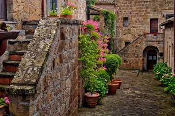 Fototapeta na wymiar Photo of romantic square in ancient town Civita in Italy with flowers and stairs