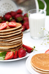 Homemade pancakes with fresh strawberries and honey.