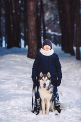 Fototapeta na wymiar Smiling Caucasian boy and his big dog in winter in a forest. The concept of winter holidays