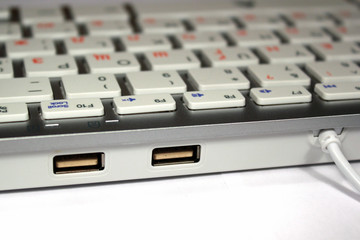 Closeup of two USB ports on computer keyboard with Russian layout and integrated USB hub