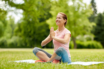 Naklejka na ściany i meble fitness, yoga and healthy lifestyle concept - happy woman meditating in summer park