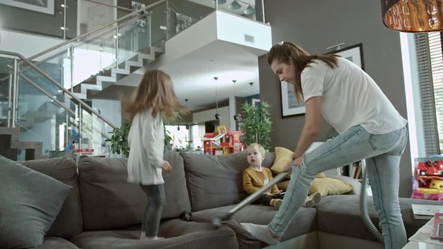 Mother cleaning a living room with kids