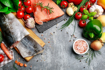 Raw fishes and vegetables on stone background