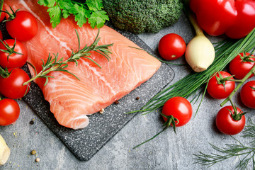 Raw fishes and vegetables on stone background