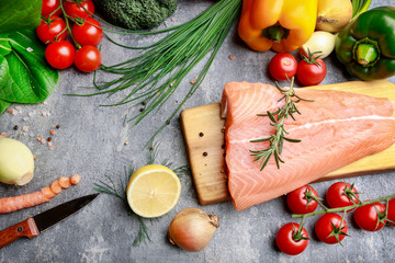 Raw fishes and vegetables on stone background