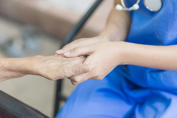 Obraz premium Hand of eldery woman with her caregiver at home. Home care or Elderly care concept.