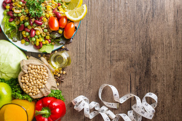 Healthy food background ,fruits and vegetables with salad bowl and measuring tape  on wooden table.