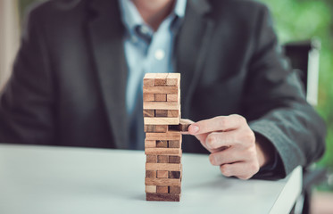 Businessman gambling placing wooden block on a tower,Risk and planing concept.