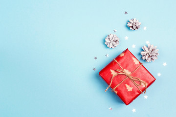 Christmas gift box with cones on blue background. Copy space for text.