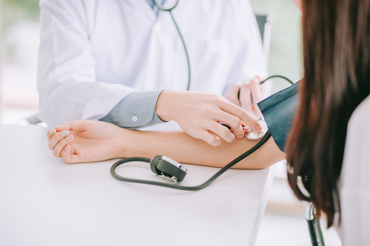 Doctor using sphygmomanometer with stethoscope checking blood pressure to a patient in the hospital.